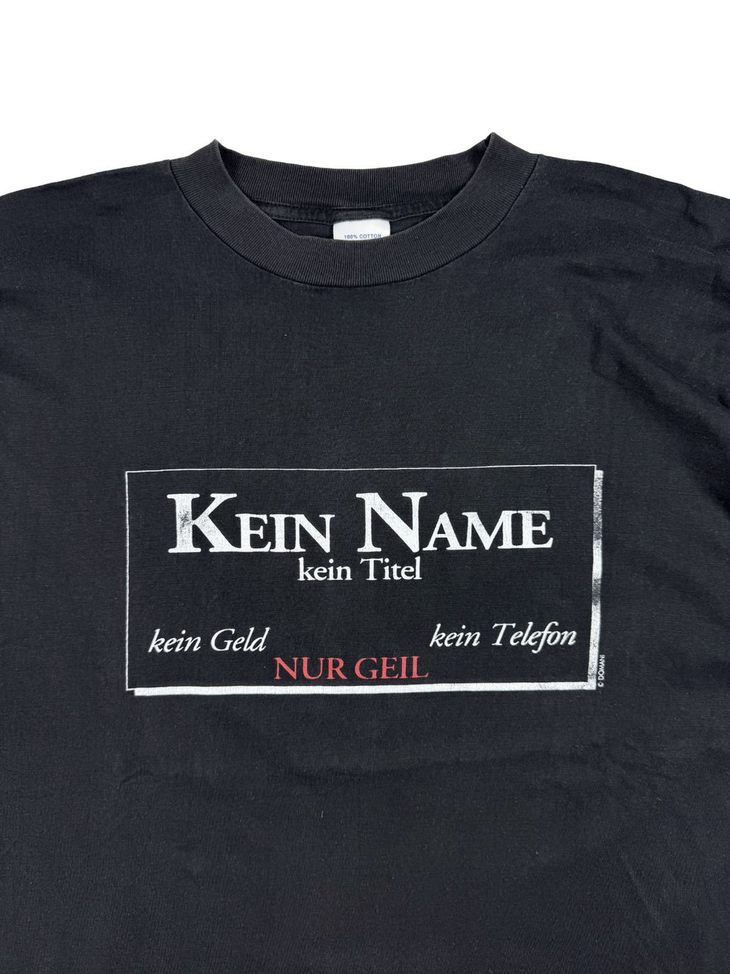 Detailansicht der Vorderseite des schwarzen Shirts mit Fokus auf den humorvollen, leicht rissigen Print: „Kein Name / kein Titel / kein Geld / kein Telefon / NUR GEIL“.