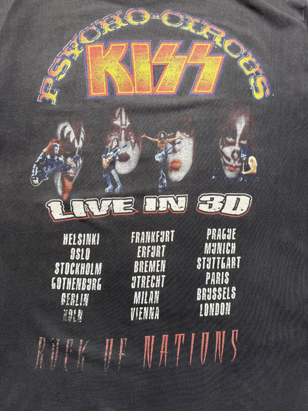 Detaillierte Ansicht des Backprints mit dem feurigen KISS-Logo, den vier Bandporträts und der Auflistung der Tourstädte wie Helsinki, Berlin, Köln, Prag und Paris.