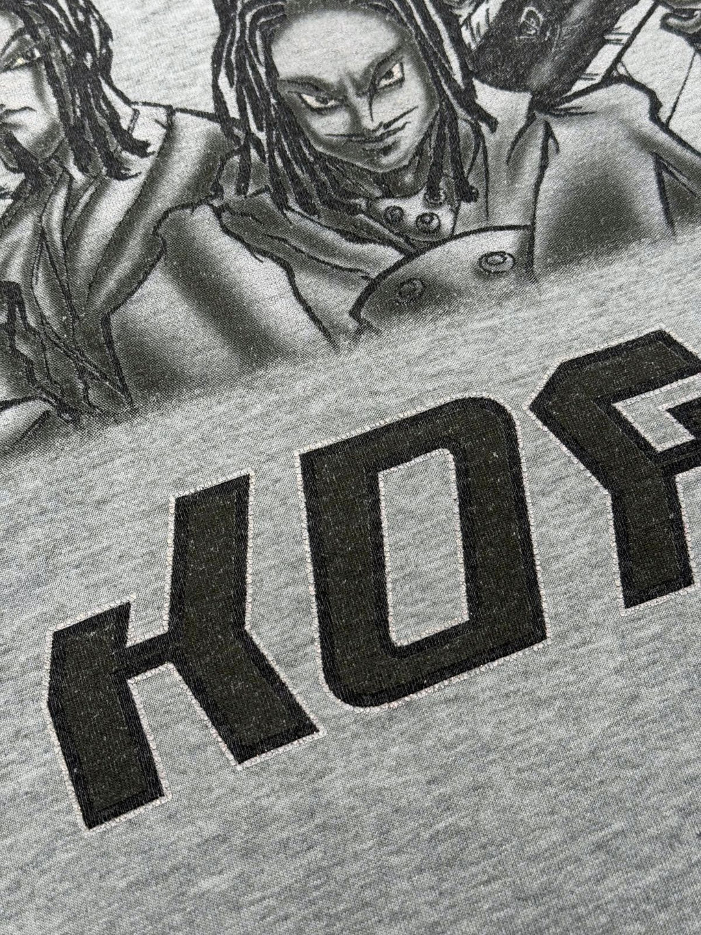 Nahaufnahme des vorderen Grafikdrucks mit Fokus auf die stilisierte japanische/Fernost-Typografie unter den Bandcharakteren.