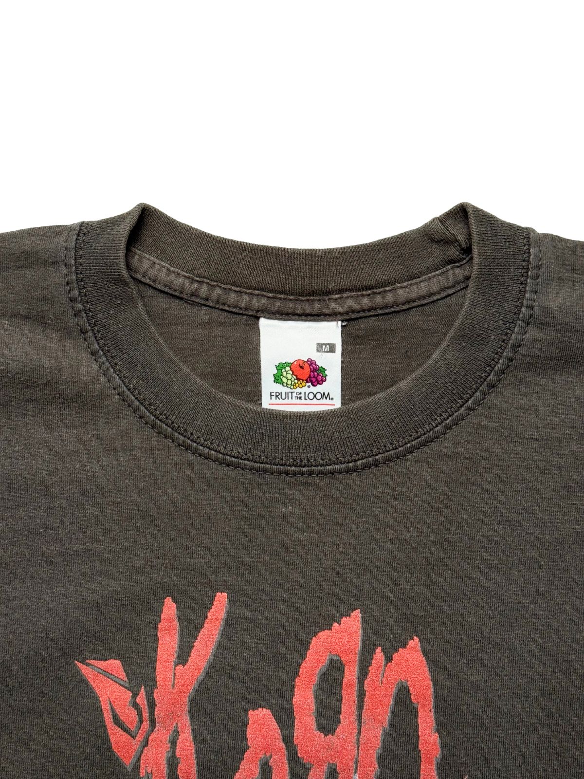 Nahaufnahme des inneren Kragens mit dem originalen weißen „Fruit of the Loom“-Nackenetikett in Größe M oberhalb des roten Band-Logos.