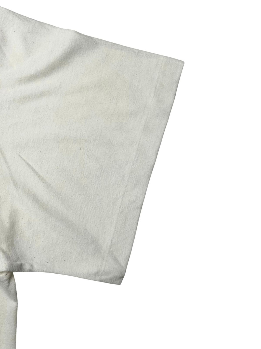 Detailansicht des Ärmels mit echter Vintage-Single-Stitch-Einfachnaht am Ärmelbund auf cremeweißem Baumwollstoff.