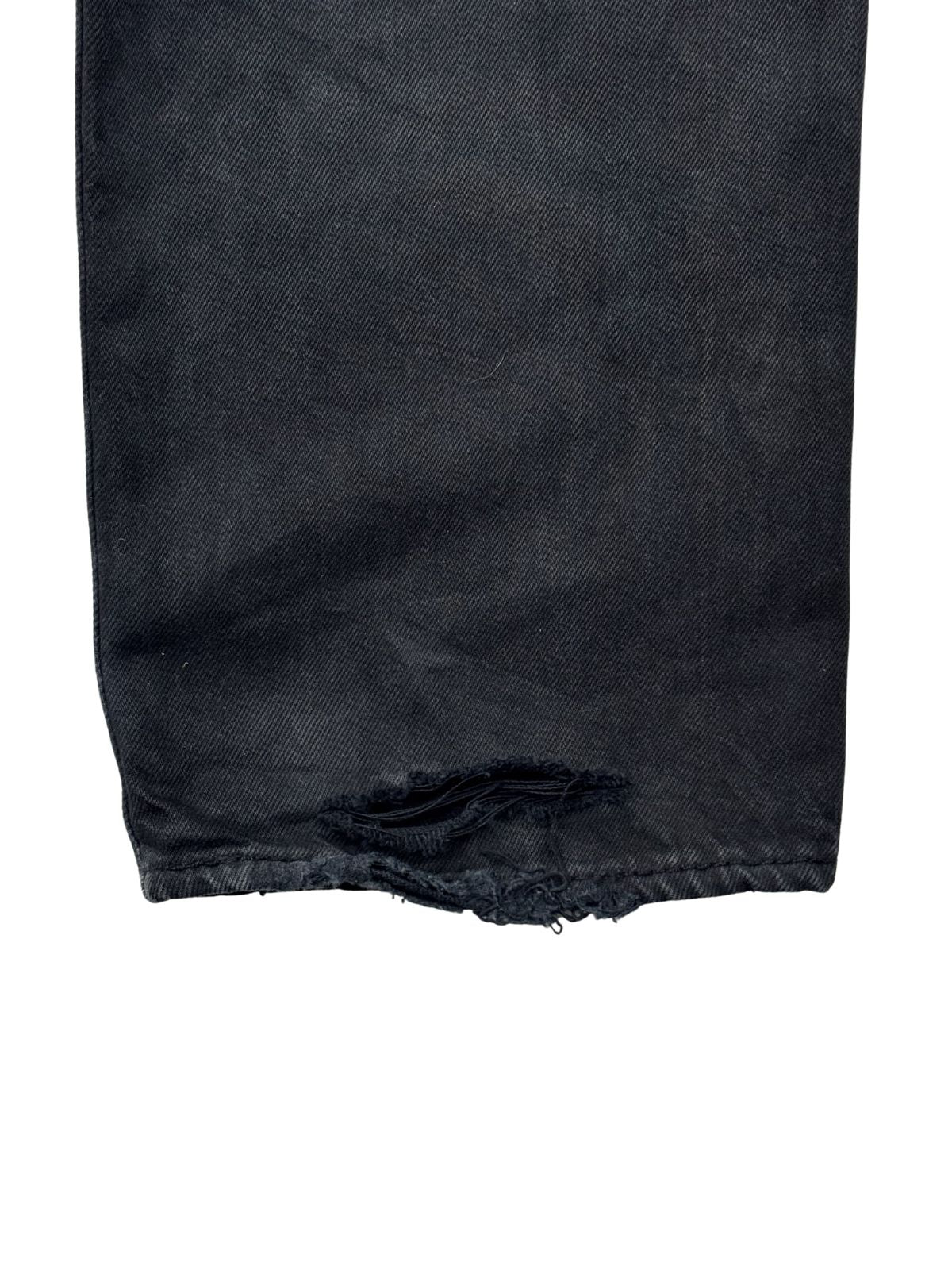 Nahaufnahme der distressed Saumkante (Heel-Bite) am rechten Bein einer schwarz gefärbten Vintage Levi's 501 Denim.
