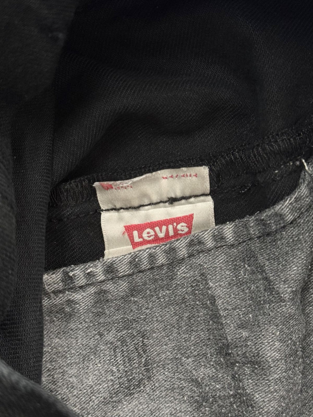 Innenansicht einer Vintage Levi's 501 Jeans mit dem klassischen roten Levi's Logo auf dem weißen Pflegeetikett und grauer Taschenfutter-Optik.