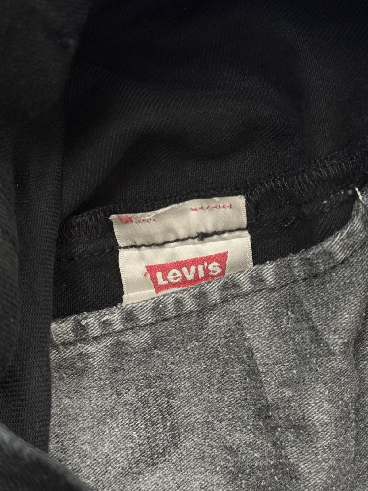 Innenansicht einer Vintage Levi's 501 Jeans mit dem klassischen roten Levi's Logo auf dem weißen Pflegeetikett und grauer Taschenfutter-Optik.
