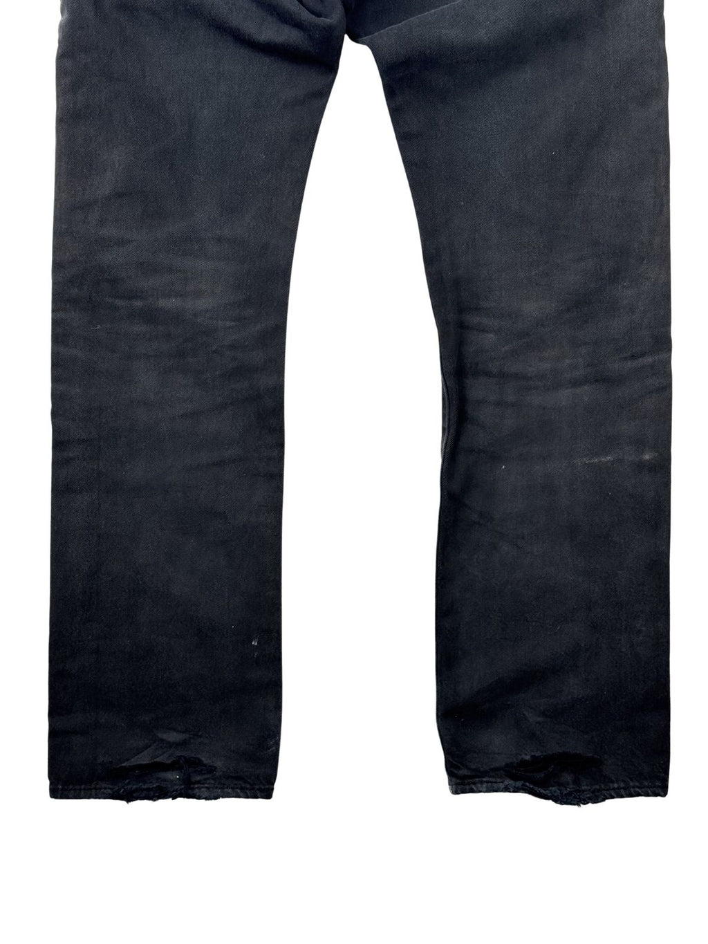 Rückansicht der unteren Beine einer schwarzen Vintage Levi's 501 Jeans mit Custom-Färbung und markanten Distressed-Effekten (Heel-Bites) an den Säumen.