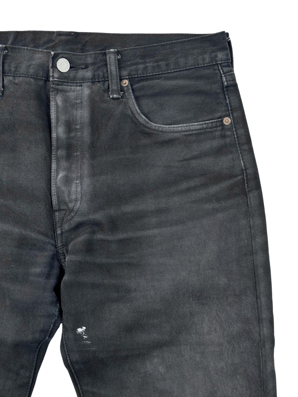 Nahaufnahme der linken Vordertasche; zeigt kleine weiße Farbspritzer und die Textur des schwarz überfärbten Denims.
