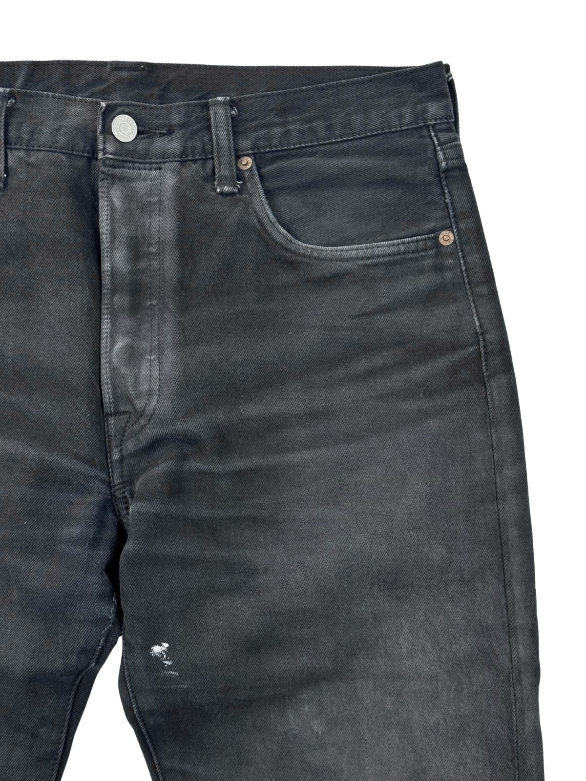 Nahaufnahme der linken Vordertasche; zeigt kleine weiße Farbspritzer und die Textur des schwarz überfärbten Denims.