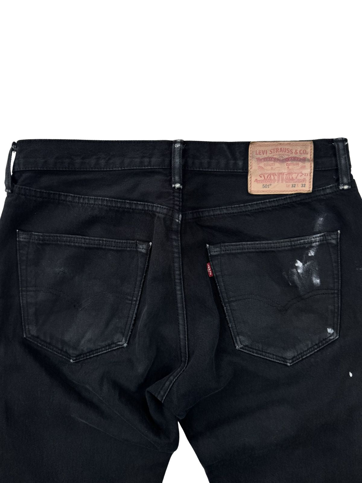 Detailansicht des Levi Strauss Leder-Labels und der rechten Gesäßtasche mit weißen Farbspritzern auf schwarzem Grund.