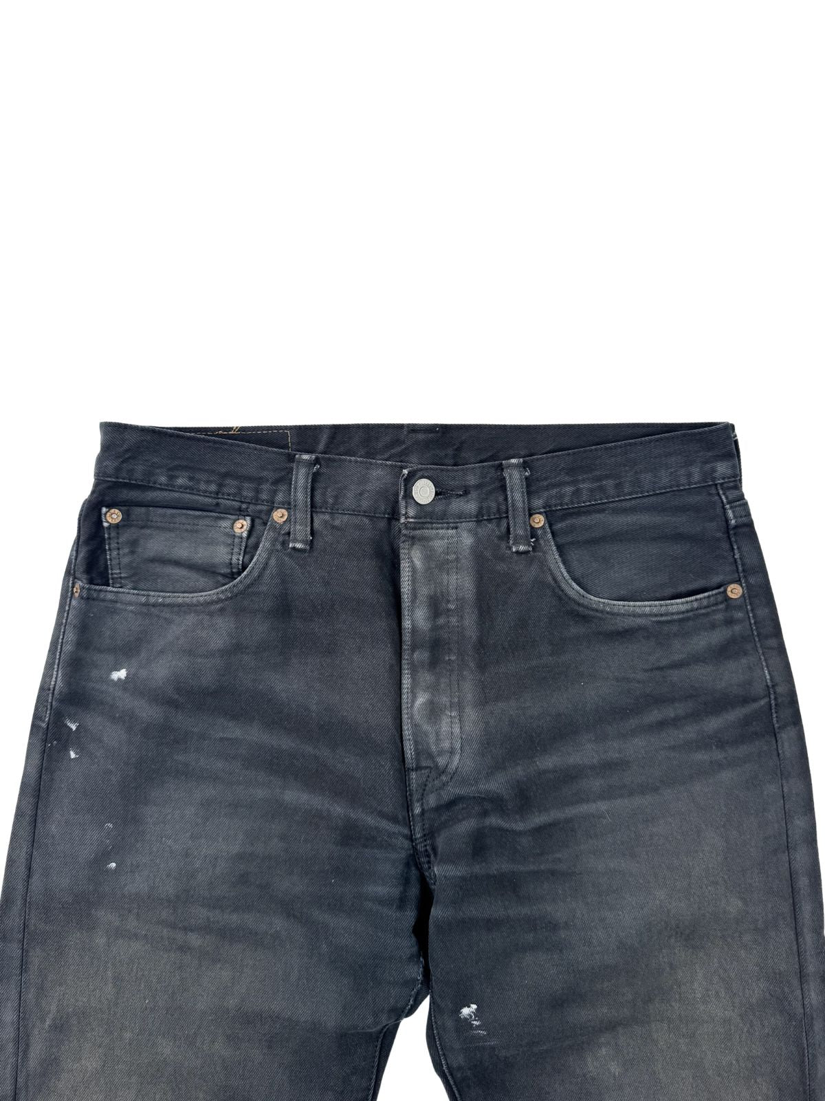 Nahaufnahme des Hosenbundes der schwarzen Levi's; zeigt den metallischen Hauptknopf, die Knopfleiste und markante Sun-Fade-Effekte im Hüftbereich.