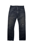 Vorderseite einer schwarz gefärbten Vintage Levi's 501 Jeans; zeigt ungleichmäßiges Fading und weiße Farbspritzer (Paint Splatter) auf dunklem Denim.