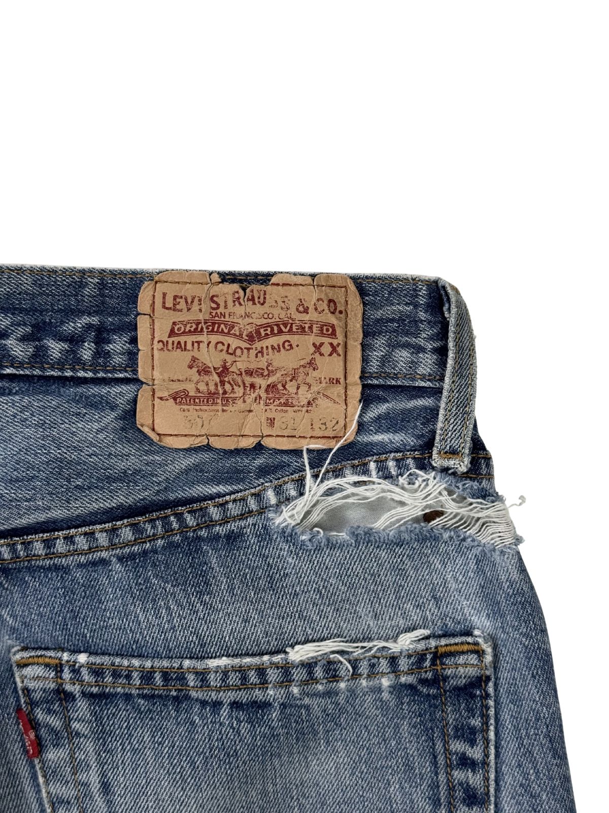 Detailansicht des verwitterten Levi's Strauss & Co. Leder-Labels am Bund; zeigt den Riss im Denim direkt unter dem Patch (Authentic Distressing).