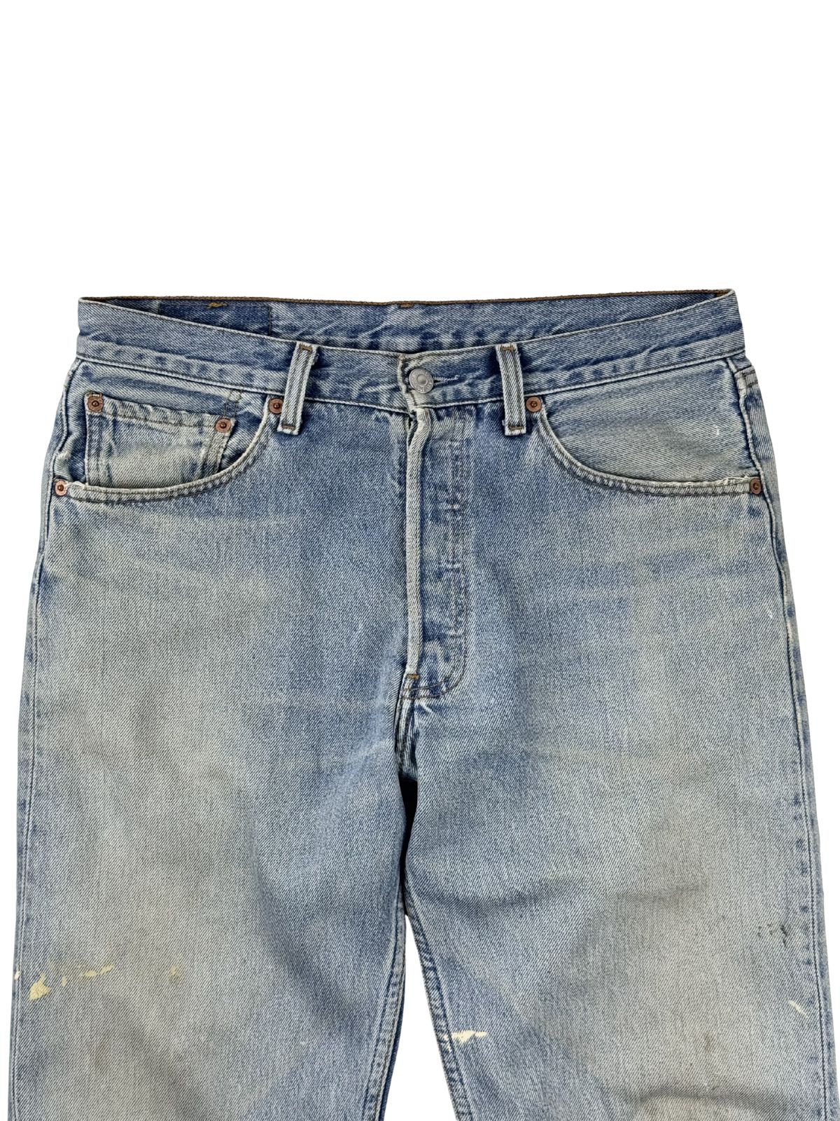 Detailaufnahme des oberen vorderen Bundes der hellblauen Levi's 501 mit dem klassischen Knopfverschluss (Button Fly) und den vorderen Taschen.
