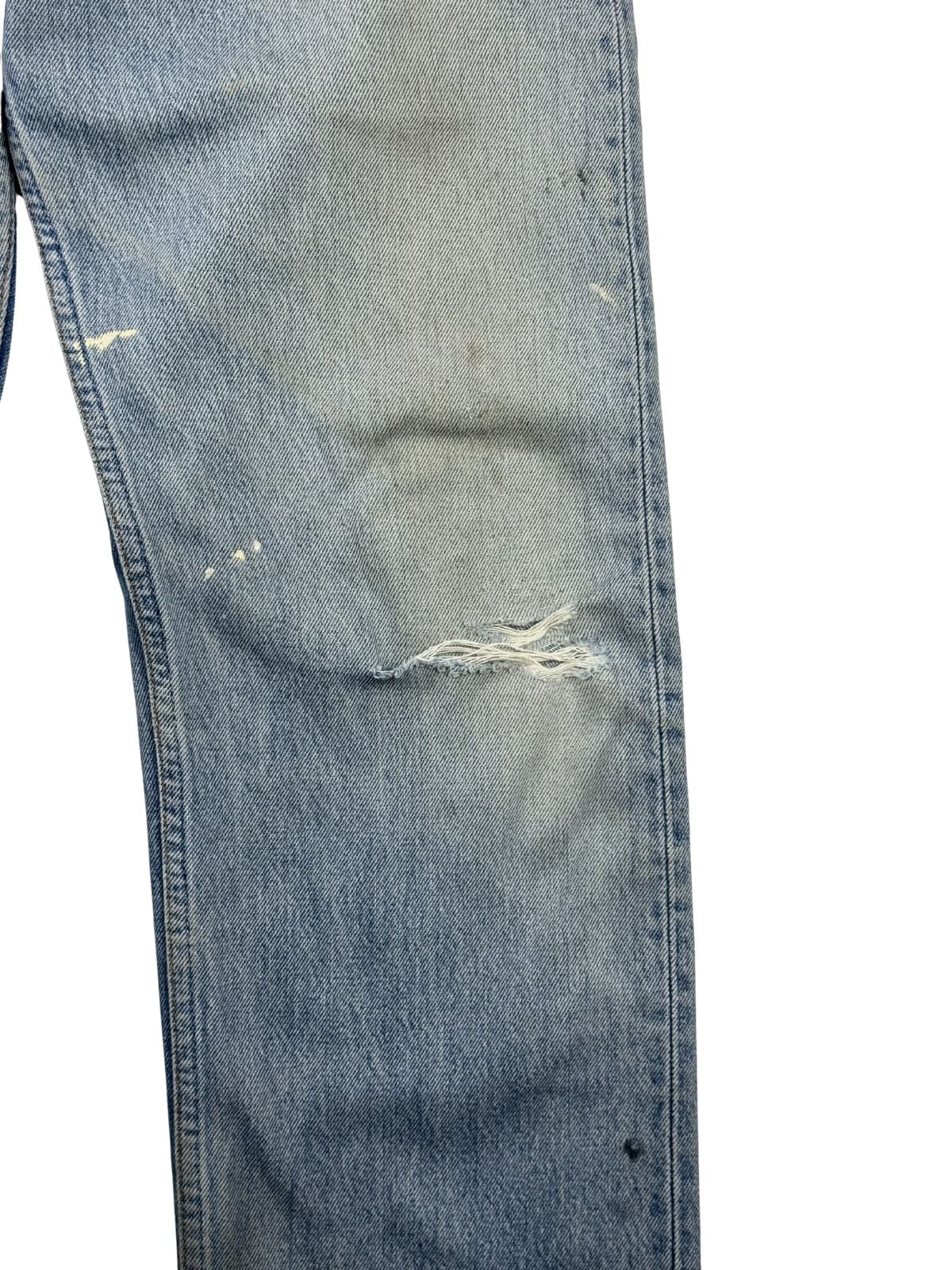 Detailaufnahme des linken Kniebereichs der Jeans mit einem horizontalen Riss und ausgefransten weißen Fäden im thrashed Used-Look.