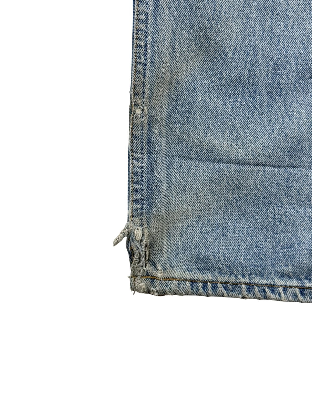 Nahaufnahme der äußeren Beinnaht direkt über dem Saum mit einer offenen, leicht aufgerissenen Webkante auf dem hellblauen Denimstoff.