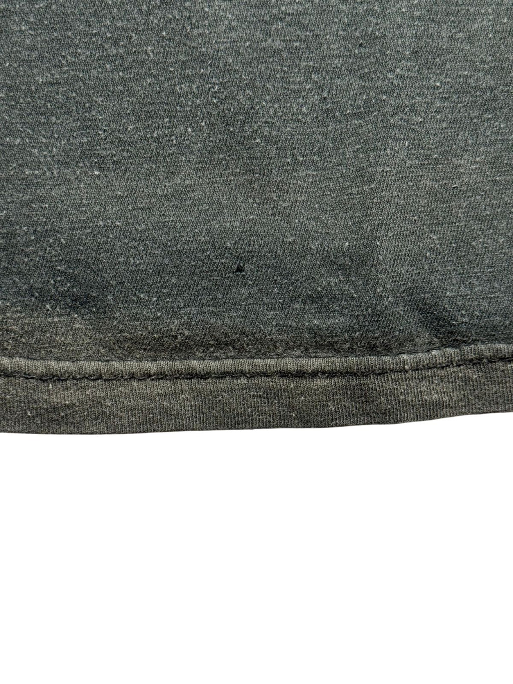 Detailaufnahme einer weiteren Stelle nahe dem Saum mit einem feinen Loch im verwaschenen Baumwollmaterial.