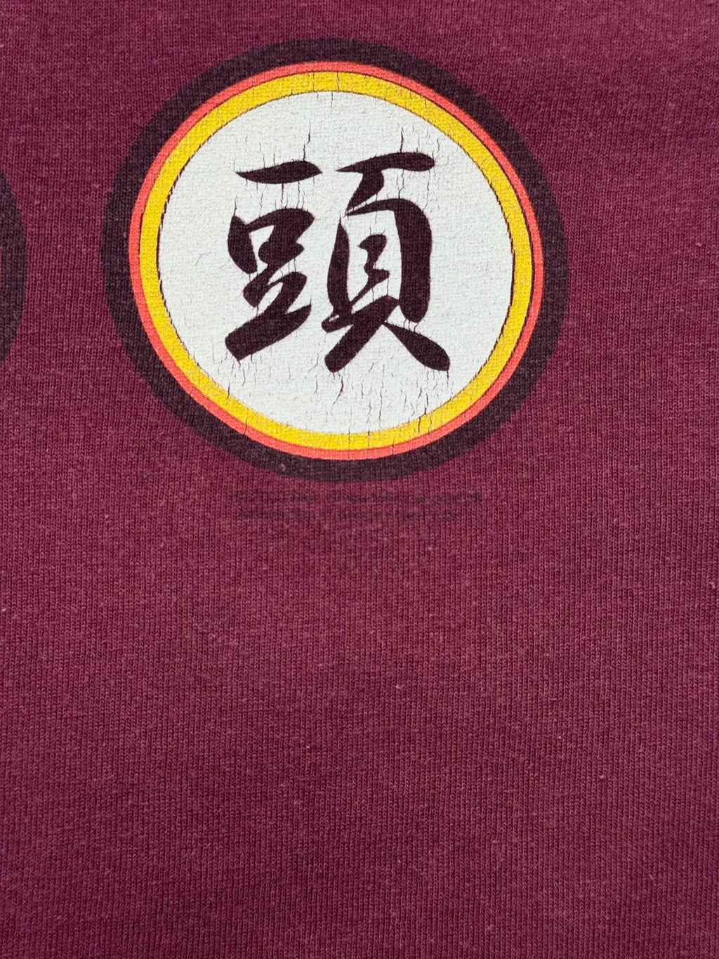 Makroaufnahme des feinen, gealterten Siebdrucks am unteren Rand des Kanji-Emblems inklusive sichtbarer Lizenzzeile.