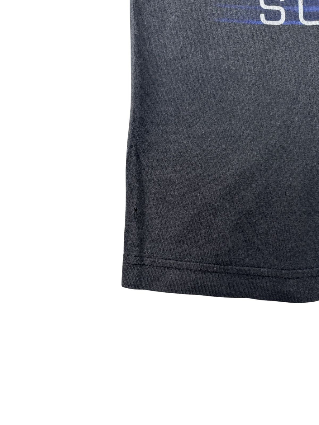 Nahaufnahme eines kleinen Lochs im schwarzen Baumwollstoff am unteren Saum des Vintage Machine Head Shirts – Zeichen von authentischem Gebrauch.