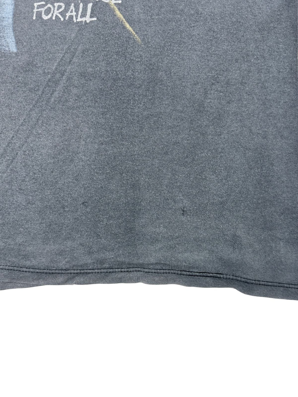 Nahaufnahme einer kleinen Reparaturstelle oder eines Lochs im unteren Rückenbereich des verwaschenen schwarzen Tank Tops.