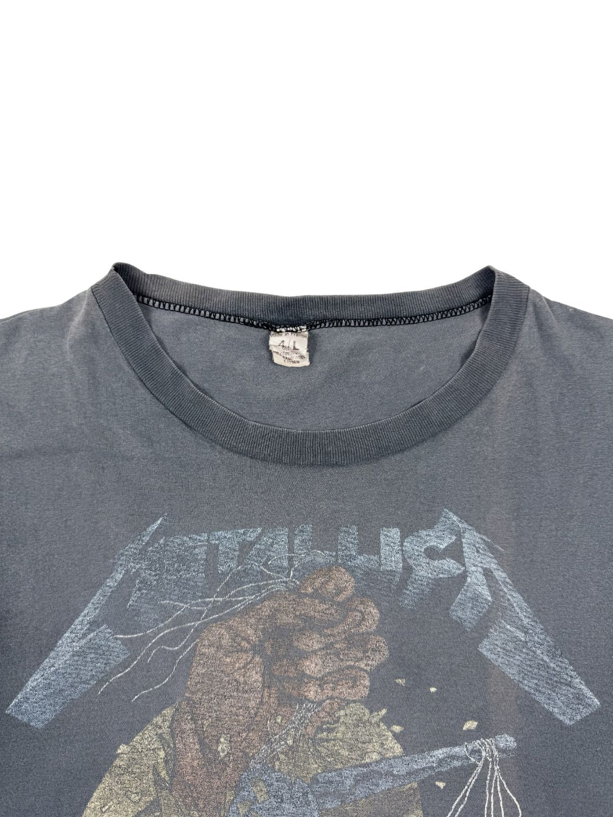Nahaufnahme des Nackenetiketts: Ein stark verwaschenes und gealtertes weißes Vintage-Tag in einem Metallica Shirt der 80er Jahre.