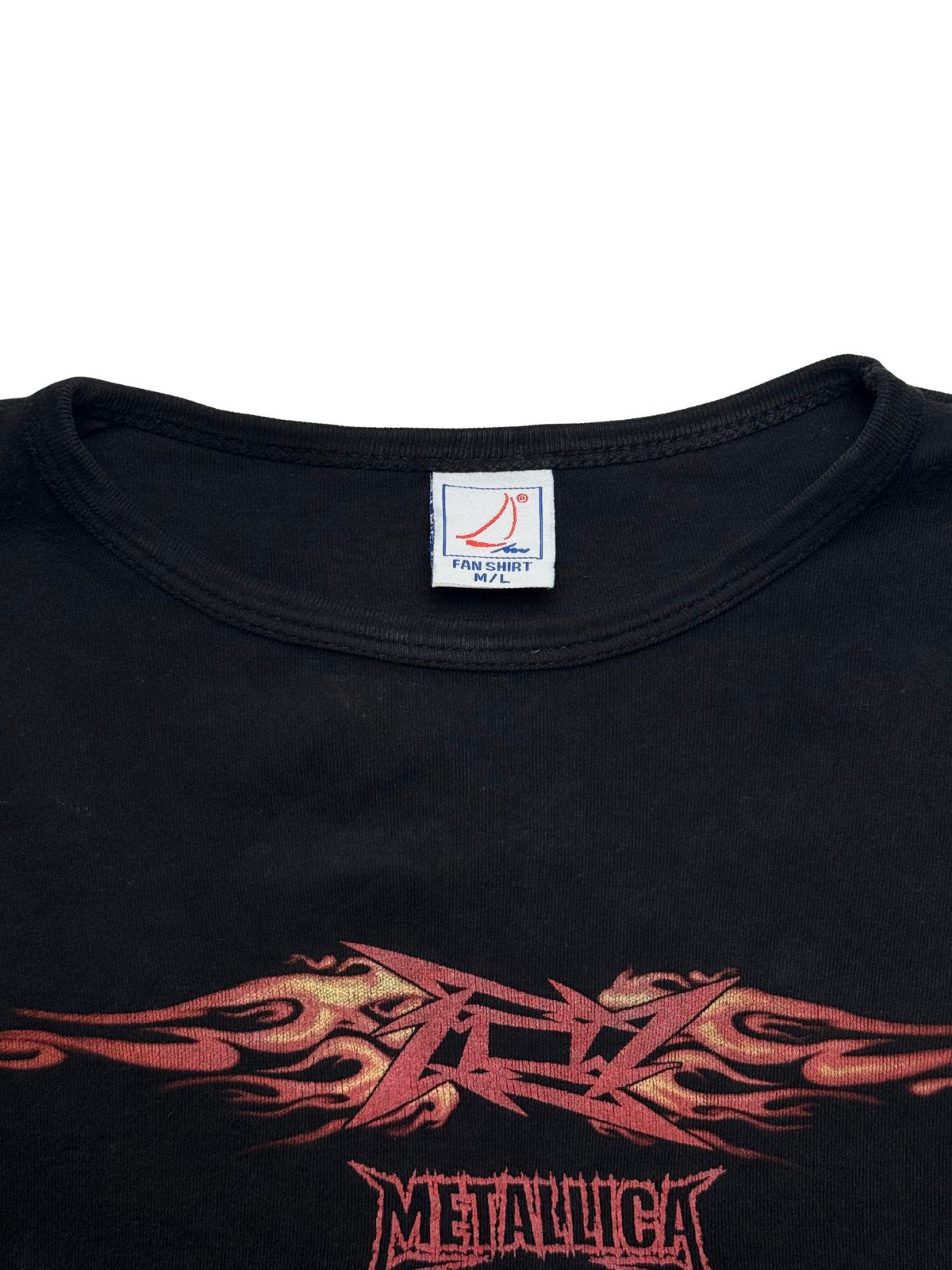 Makroaufnahme des Kragenbereichs mit dem originalen quadratischen Segelboot-Logo-Etikett der Marke „FAN SHIRT“ (Größe M/L) oberhalb des Flammen-Prints.