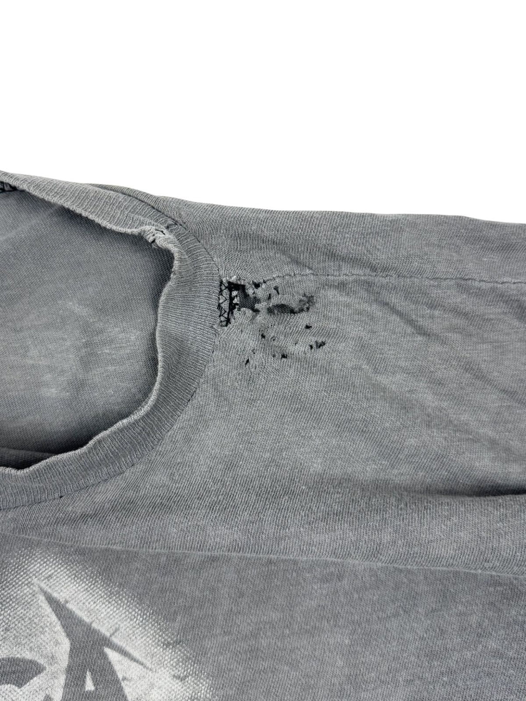Transparente Nahaufnahme von mehreren Löchern und Abnutzungen im Schulterbereich; klassischer „Thrashed Vintage“ Zustand eines 80s Rock-Shirts.
