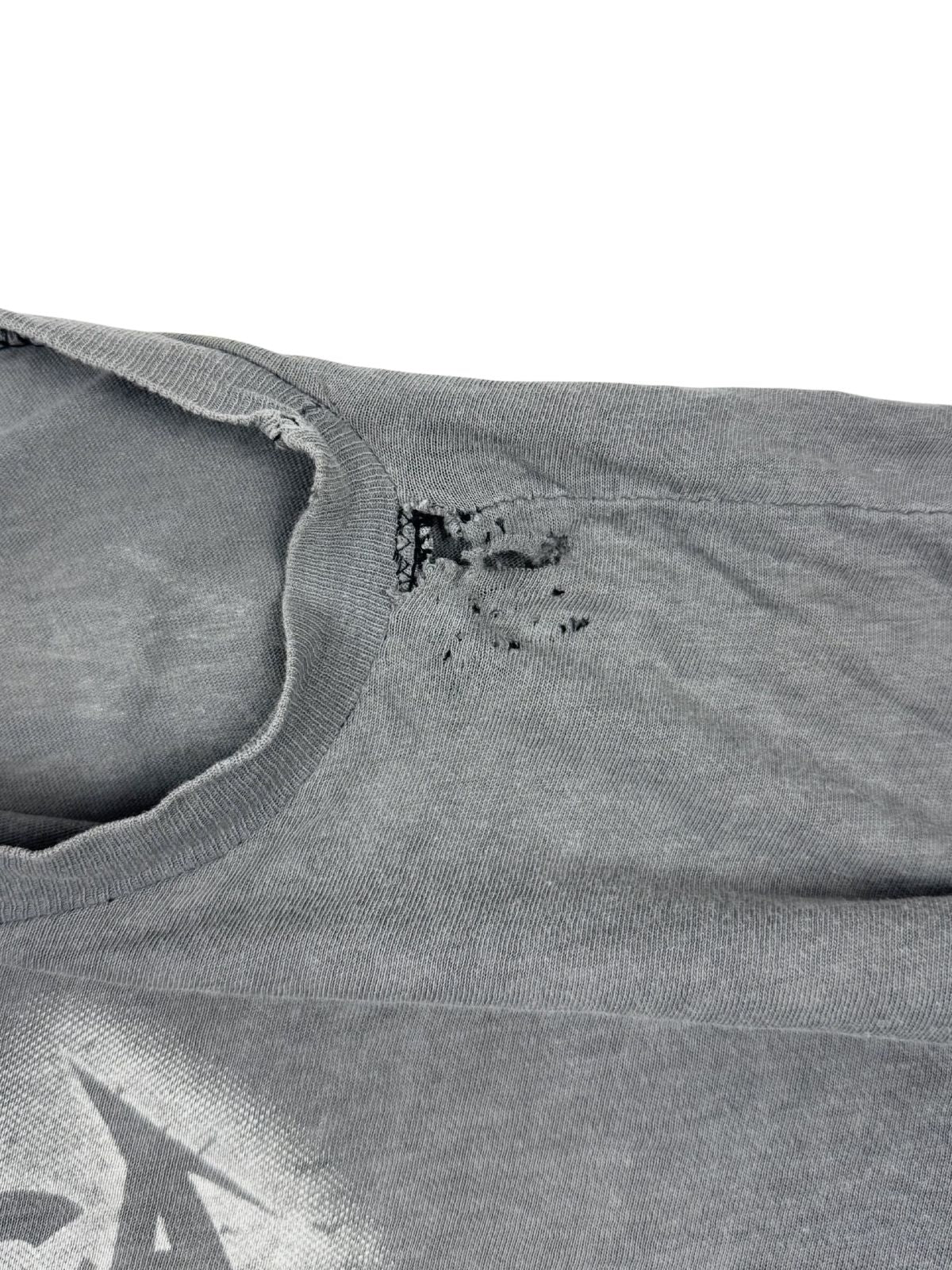 Transparente Nahaufnahme von mehreren Löchern und Abnutzungen im Schulterbereich; klassischer „Thrashed Vintage“ Zustand eines 80s Rock-Shirts.