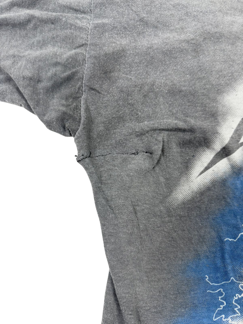 Nahaufnahme einer groben Naht-Reparatur unter dem Ärmel; unterstreicht den authentisch gelebten Charakter des über 35 Jahre alten Band-Shirts.