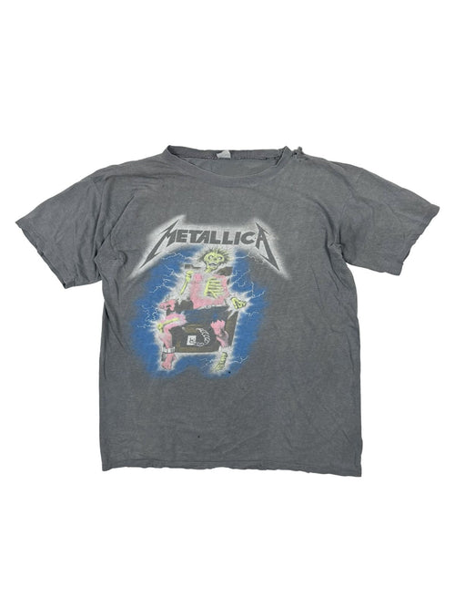 Foto 1 (Vorderansicht flach): Vorderseite eines extrem verwaschenen, grauen Metallica Vintage Shirts von 1987; zeigt das seltene „Electric Chair Skeleton“-Motiv mit Blitzen in Blau und Pink.