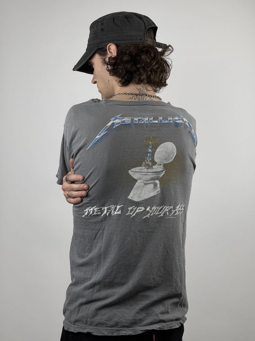 Rückansicht des getragenen Band-Shirts; verdeutlicht den Boxy-Schnitt und die Platzierung der Rücken-Grafik auf dem hellgrau verwaschenen Stoff.