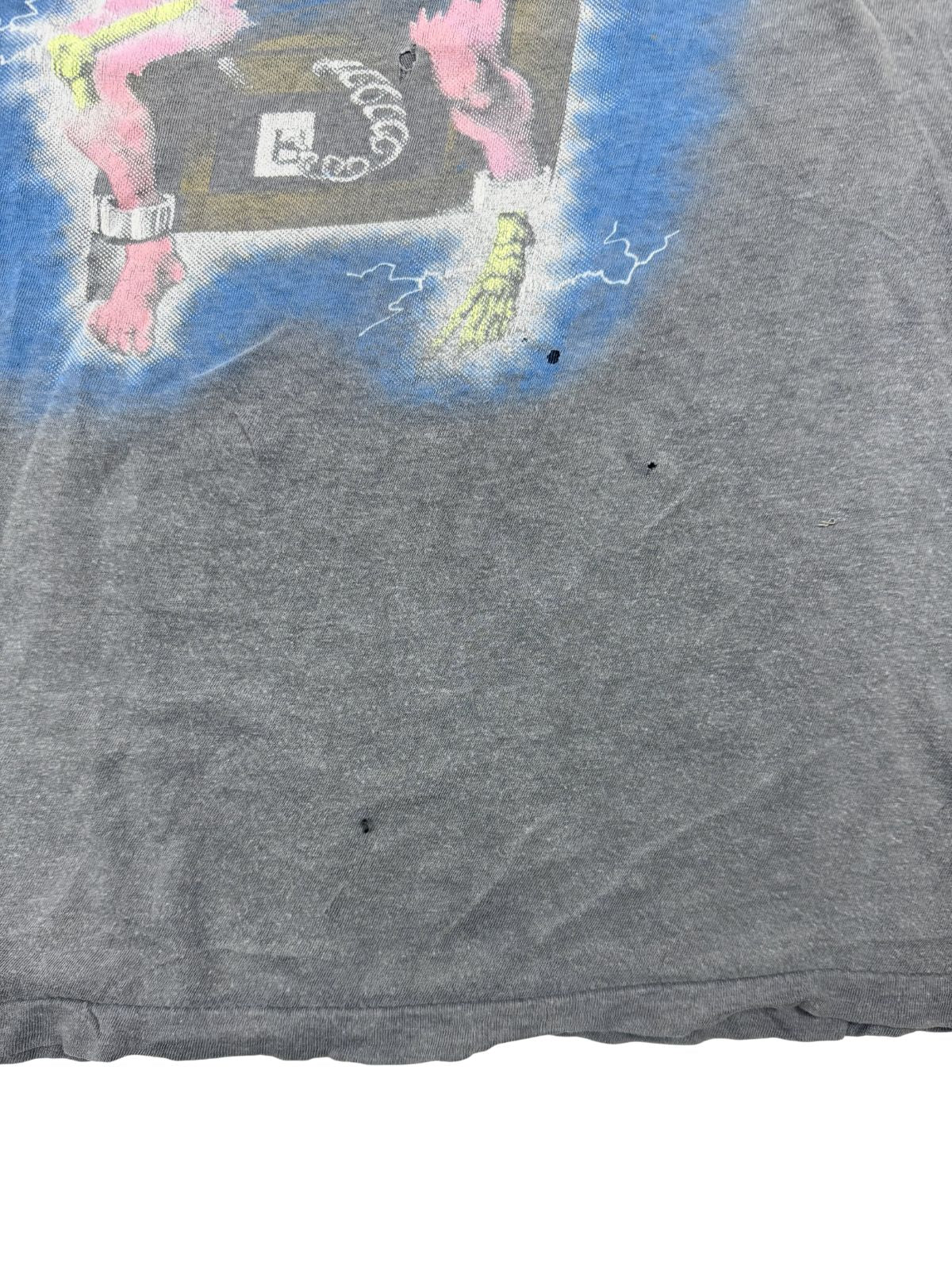 Nahaufnahme des unteren Saums des Metallica Shirts; zeigt kleine Löcher (Pinholes) im grauen Vintage-Stoff und die authentische „Single Stitch“ Naht (Einzelnaht) als Beleg für die Originalität aus den 80ern.