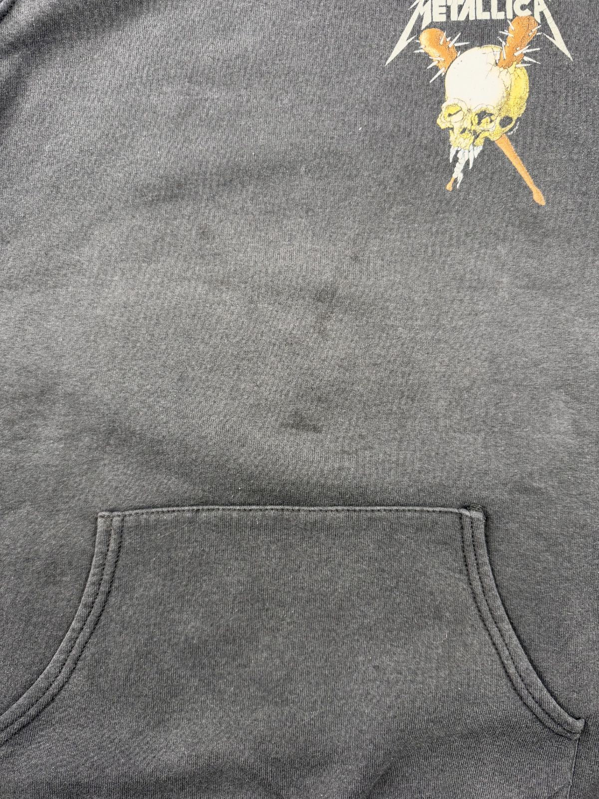 Nahaufnahme der verwaschenen schwarzen Baumwollstruktur des Hoodies im Bereich der Kängurutasche mit leichten Vintage-Gebrauchsspuren.