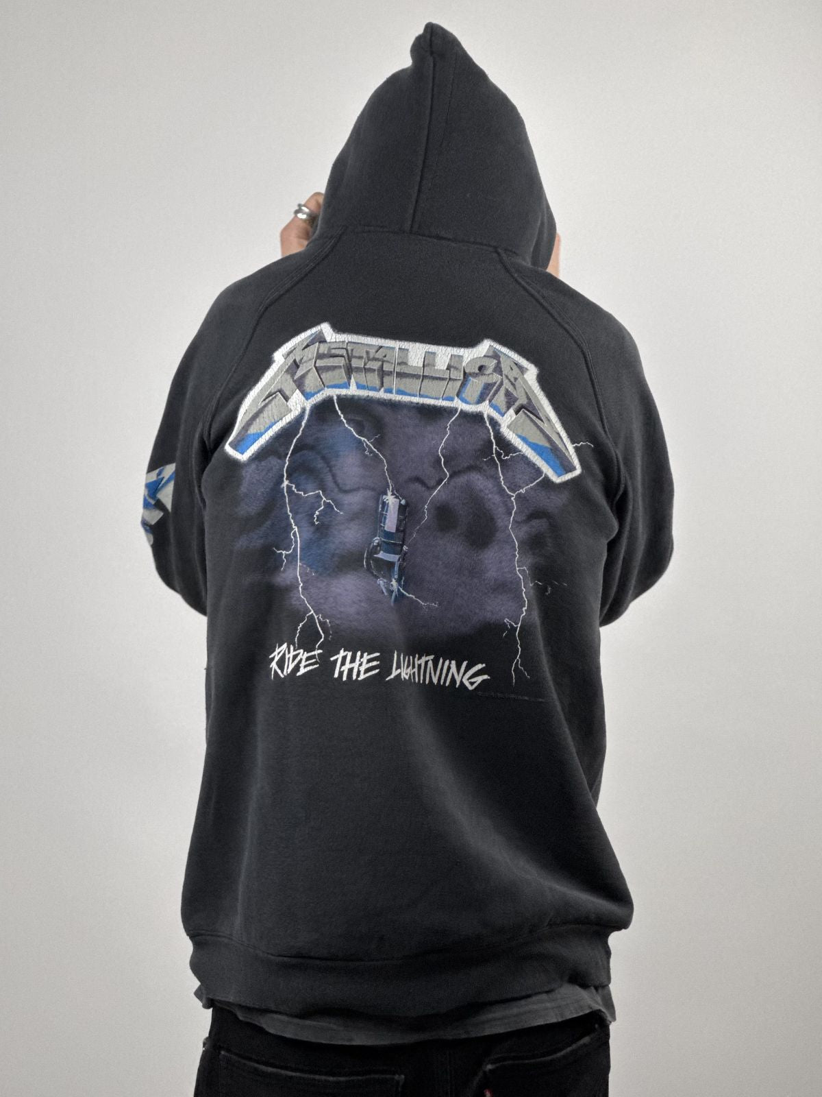 Eine Person trägt den Vintage Metallica Ride the Lightning Hoodie; Fokus auf dem großflächigen Rückenprint und der lockeren Passform.