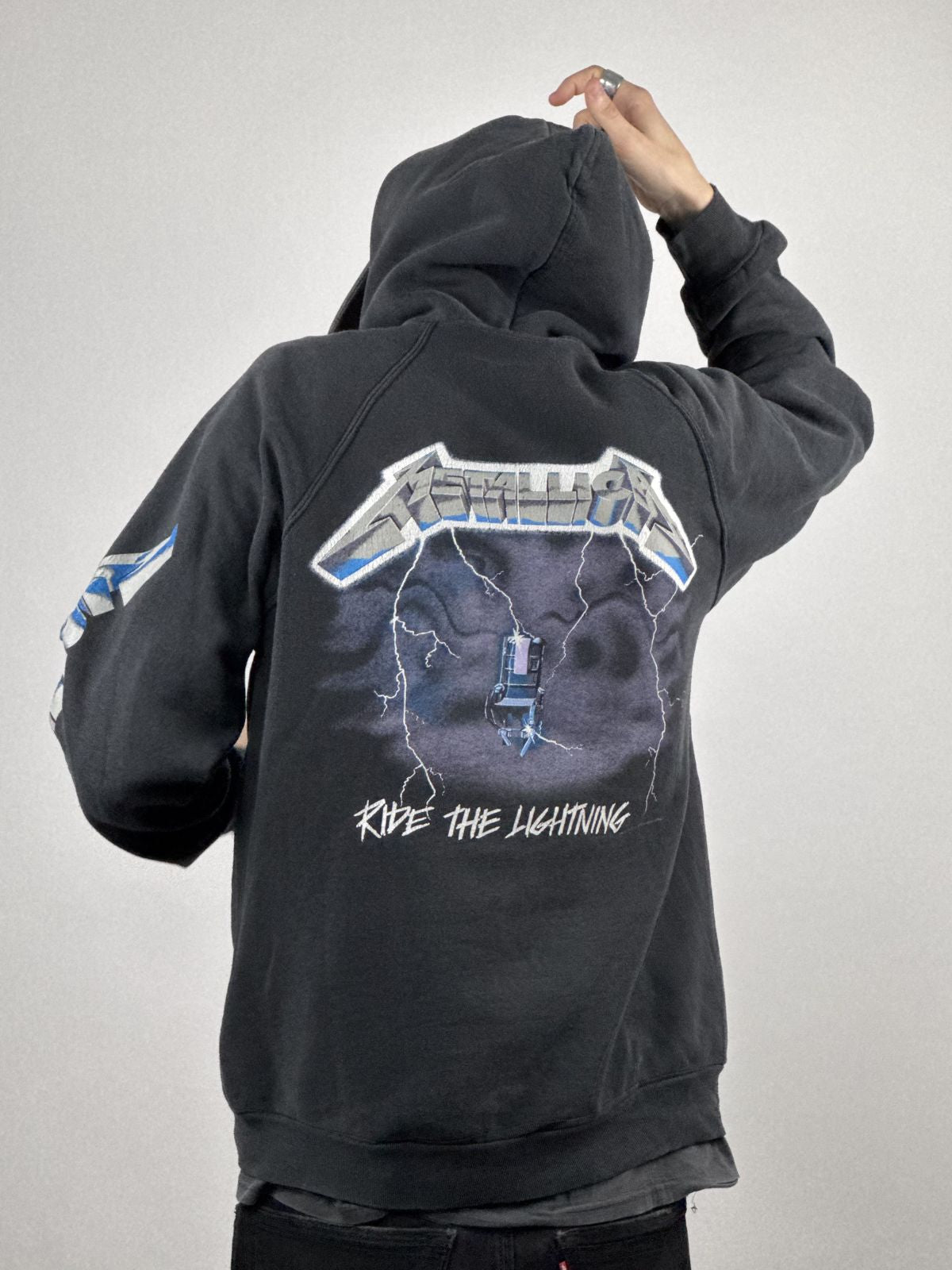 Rückseitige Ansicht des getragenen Band-Hoodies, die das Metallica-Logo-Design auf dem Ärmel und den Vintage-Look verdeutlicht.