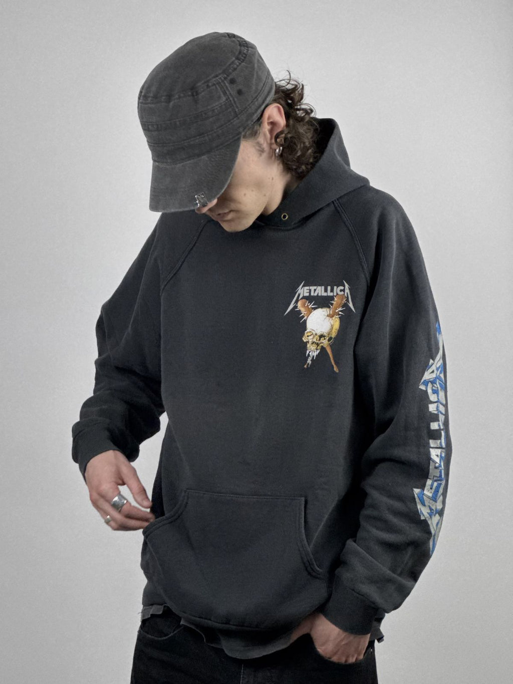Eine Person mit Mütze trägt den schwarzen Metallica-Hoodie von 1994; Ansicht des Brustprints und des markanten Ärmel-Aufdrucks.