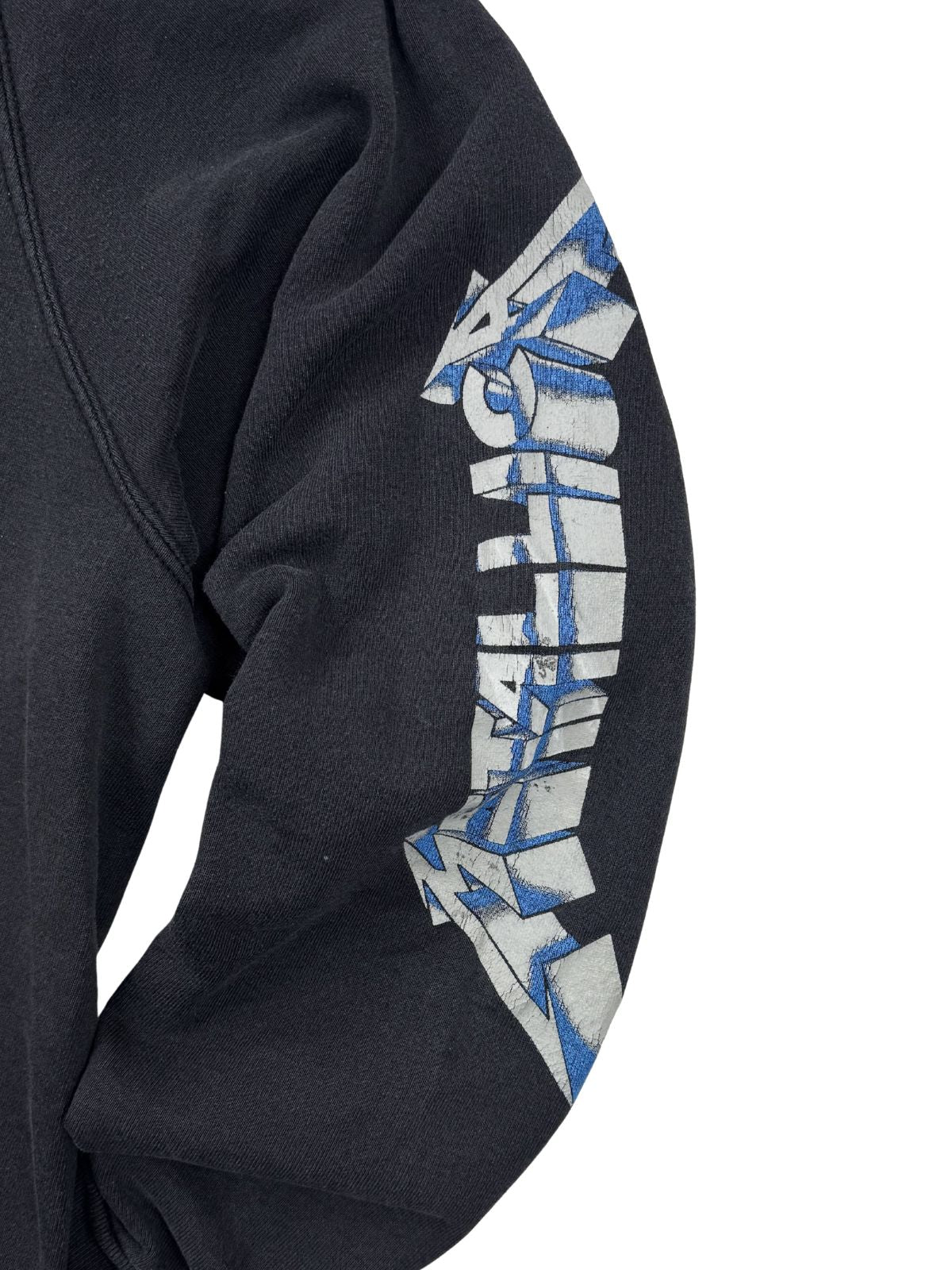 Nahaufnahme des aufgedruckten Metallica-Logos am Ärmel. Das 3D-Design ist in Weiß und Blau gehalten, passend zum „Ride the Lightning“-Artwork, und zeigt leichte Abnutzungsspuren (Cracking).