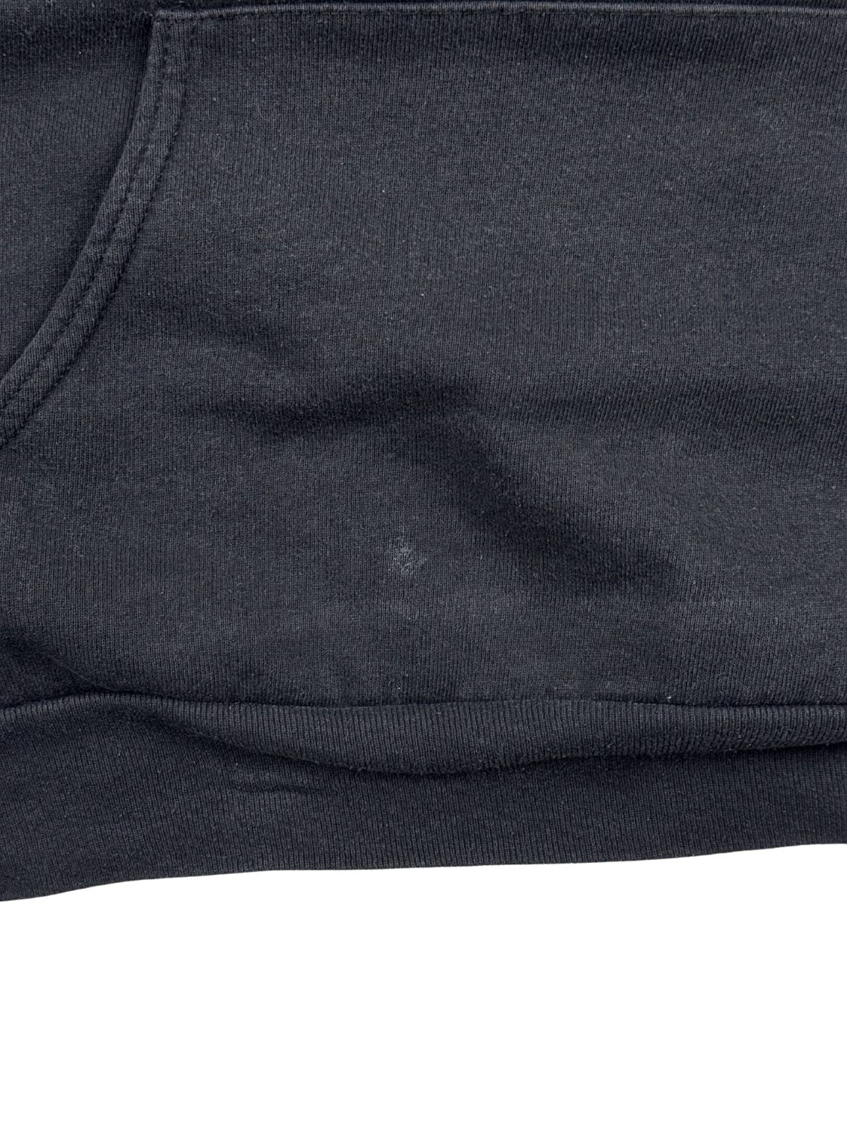 Detailaufnahme der Vorderseite direkt über dem elastischen Bund. Auf dem schwarzen Stoff neben der Kängurutasche ist ein kleiner, heller Fleck zu sehen.