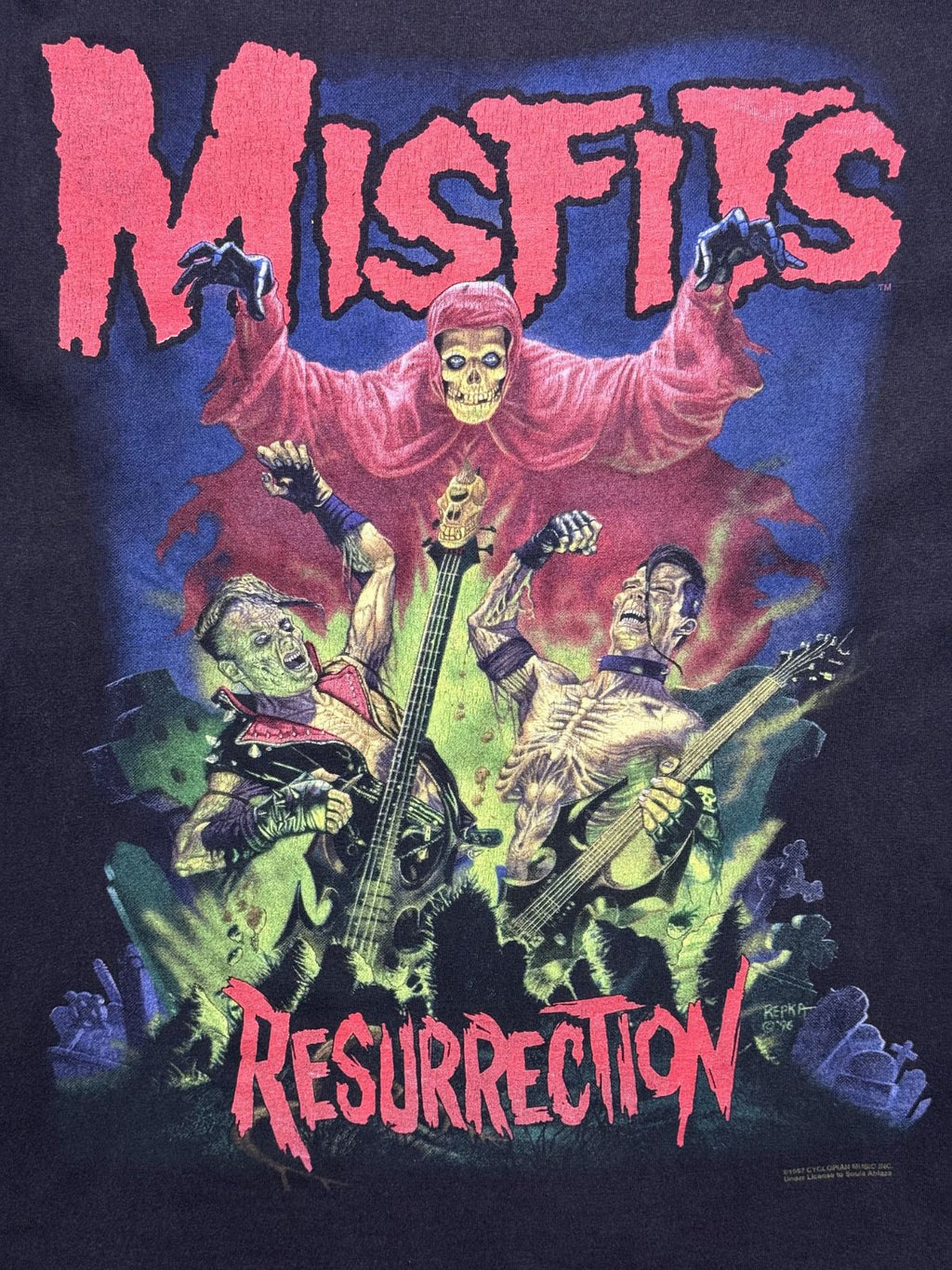 Detailansicht des vorderen Siebdrucks von Pushead/Ed Repka: Misfits-Schriftzug in Pink über Skelett-Figuren auf dem Friedhof mit der Aufschrift „RESURRECTION“.