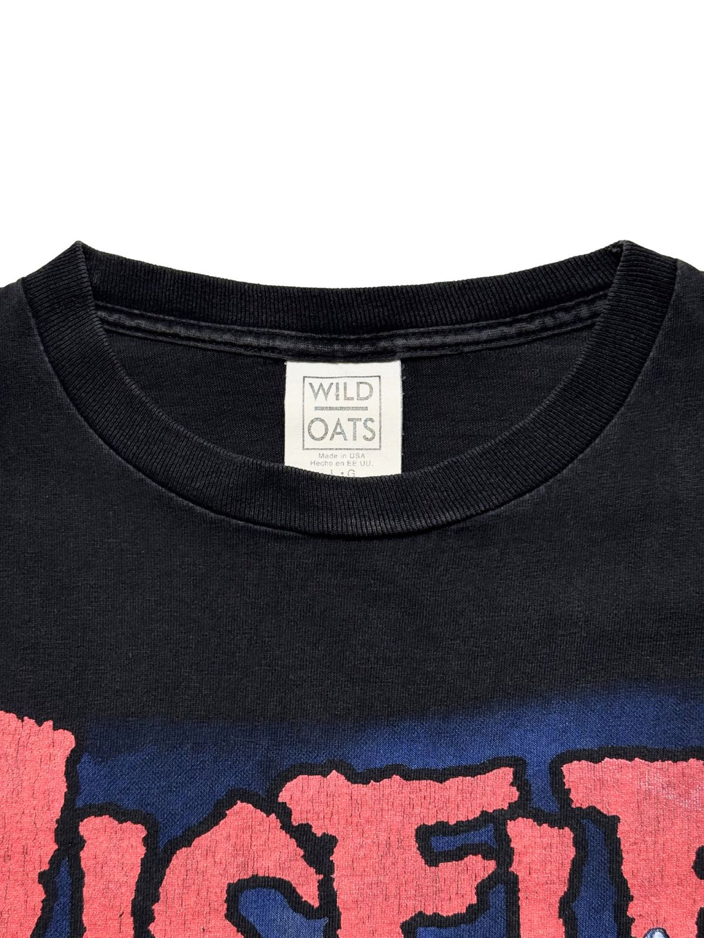 Nahaufnahme des Nackenbereichs mit dem originalen, gut erhaltenen weißen „Wild Oats“-Stoffetikett (Made in USA, Größe L).