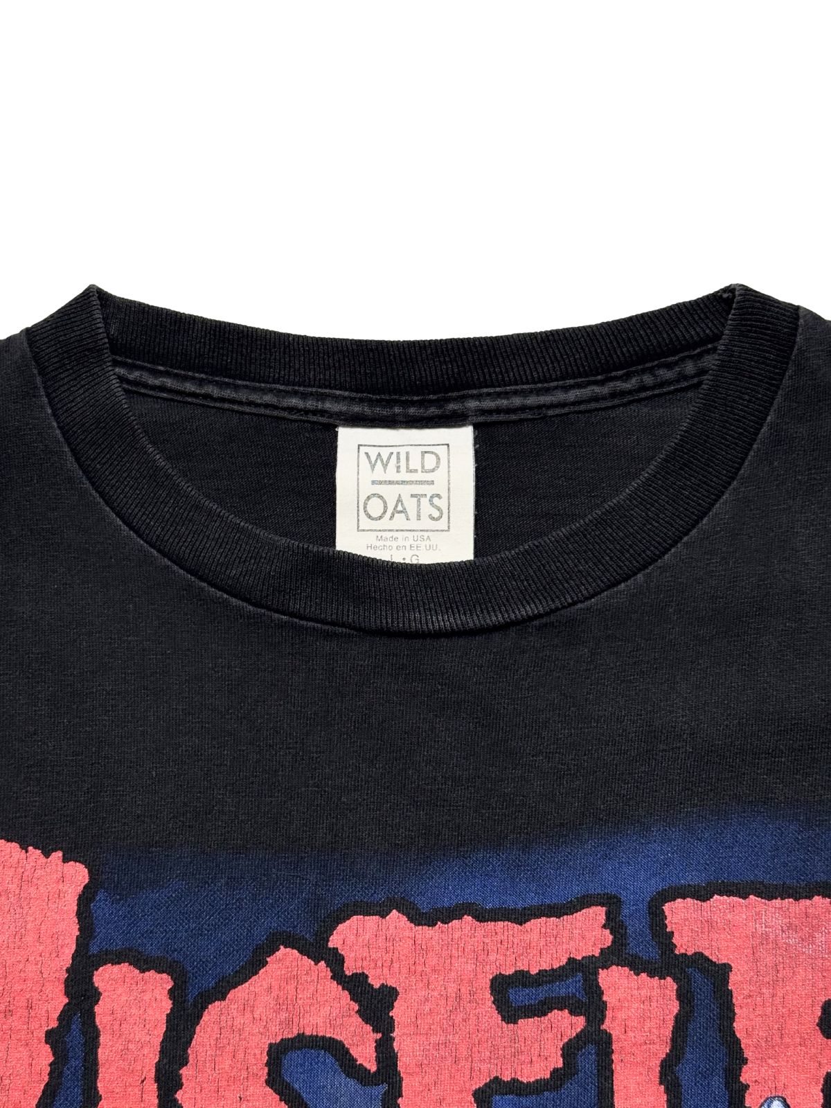 Nahaufnahme des Nackenbereichs mit dem originalen, gut erhaltenen weißen „Wild Oats“-Stoffetikett (Made in USA, Größe L).