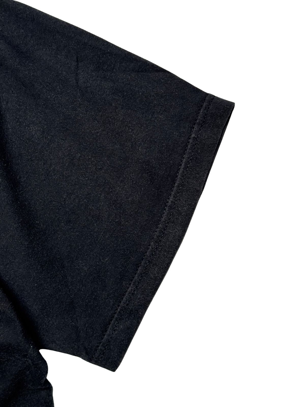 Detailansicht des kurzen Ärmelbunds mit sauberer Doppelnaht auf dem leicht verwaschenen schwarzen Baumwollmaterial.
