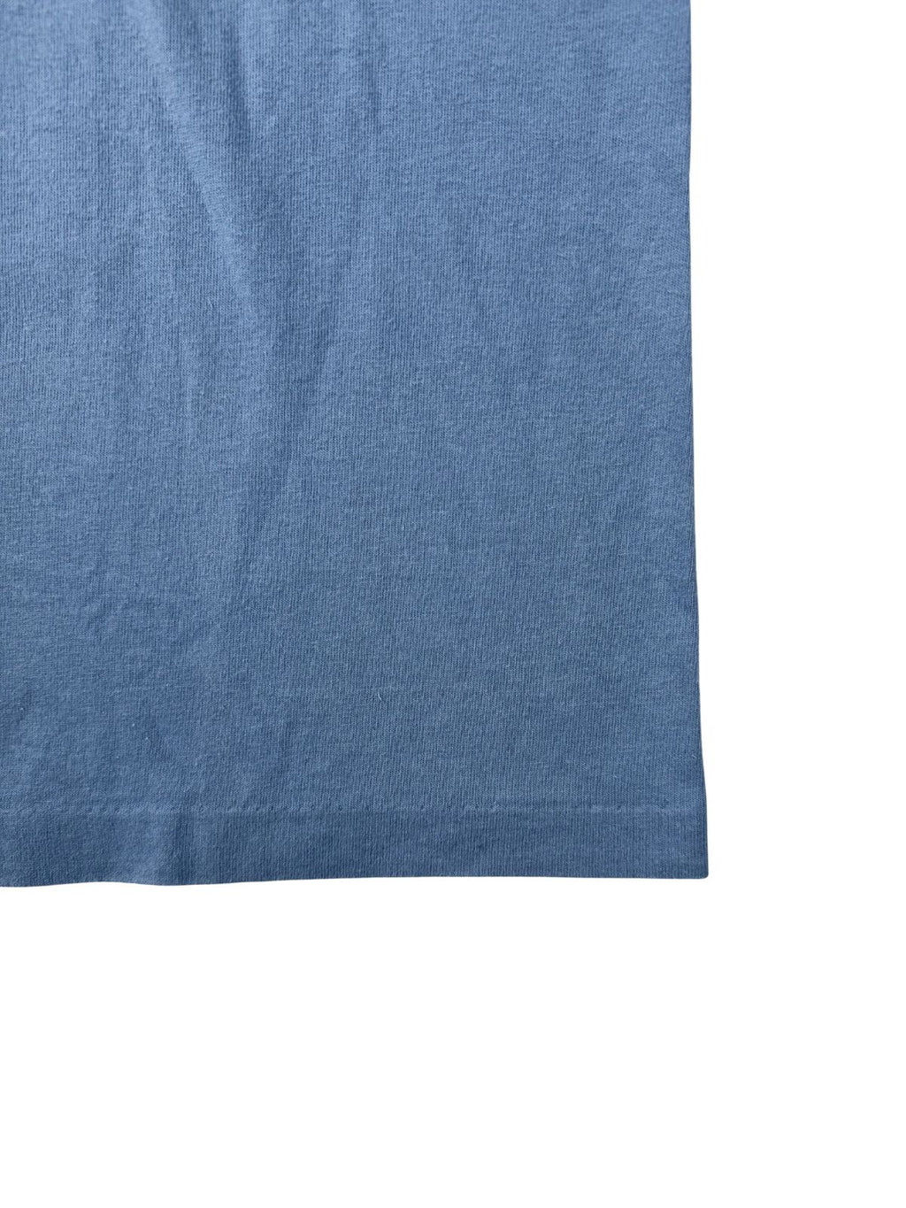 Nahaufnahme des unteren Saums mit Single-Stitch-Verarbeitung auf dem hellblauen, leicht verwaschenen Stoff.