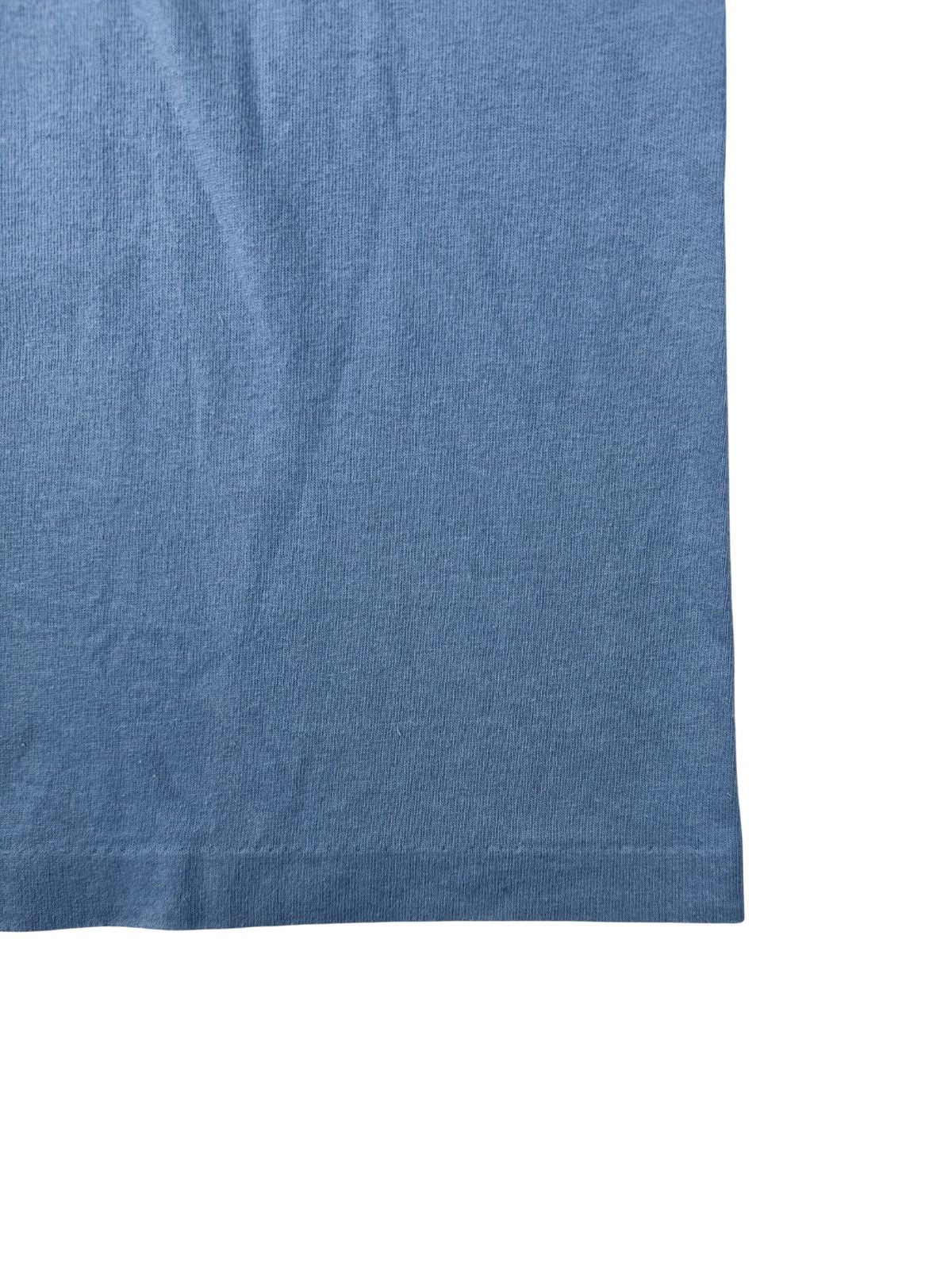 Nahaufnahme des unteren Saums mit Single-Stitch-Verarbeitung auf dem hellblauen, leicht verwaschenen Stoff.