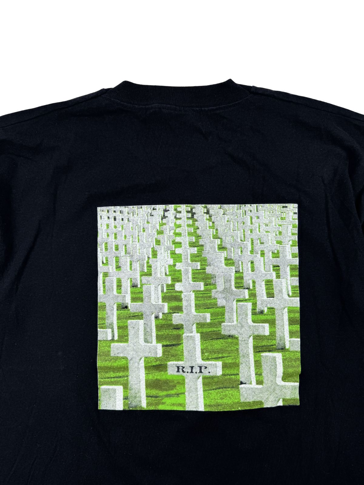 Detaillierte Nahaufnahme des Backprints, der einen Friedhof mit Grabkreuzen darstellt, wobei auf dem vordersten Kreuz die Aufschrift „R.I.P.“ zu lesen ist.
