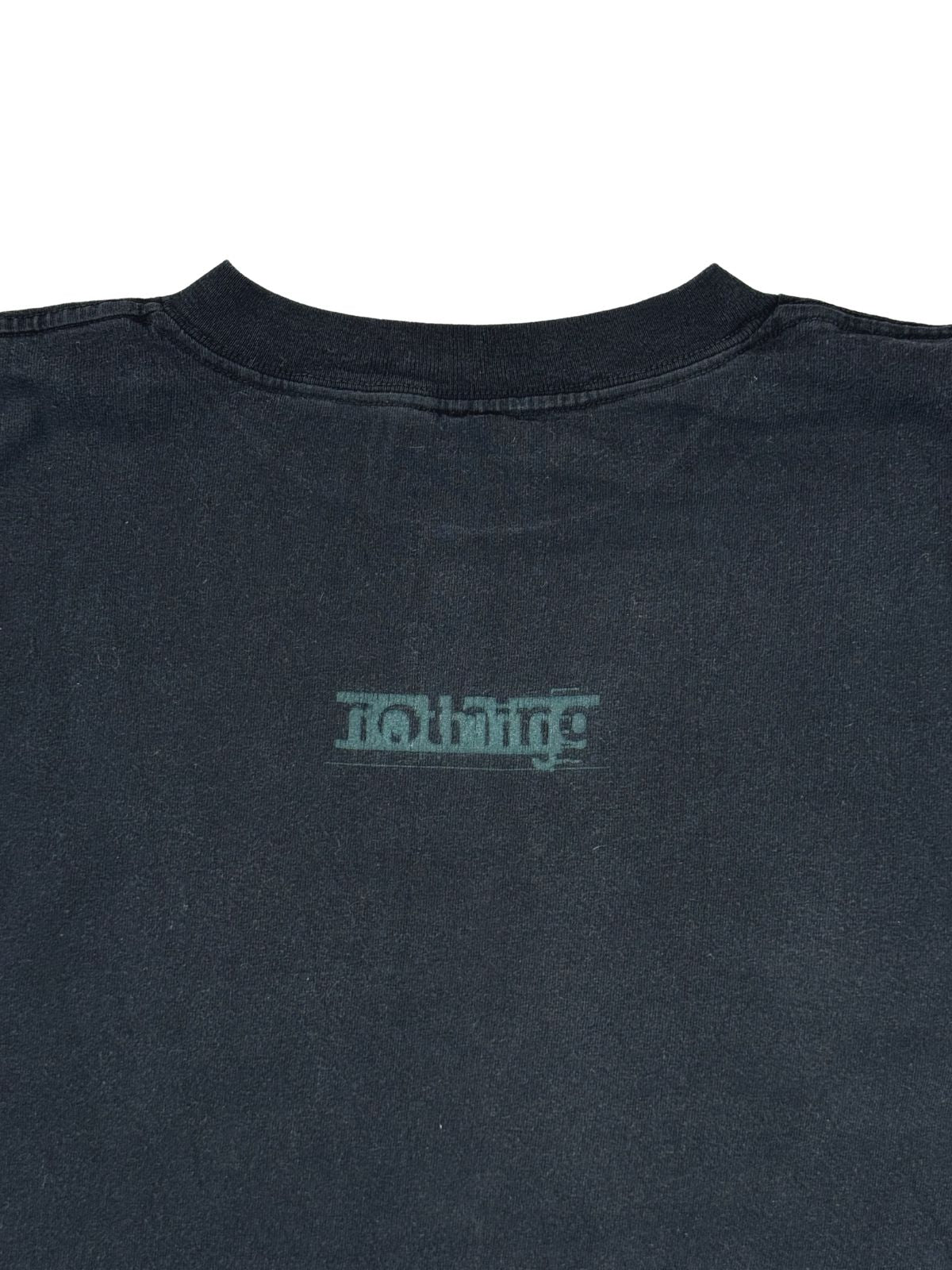 Nahaufnahme der oberen Rückseite des Shirts mit Fokus auf den Halsausschnitt und das darunter platzierte „nothing“-Plattenlabel-Logo.