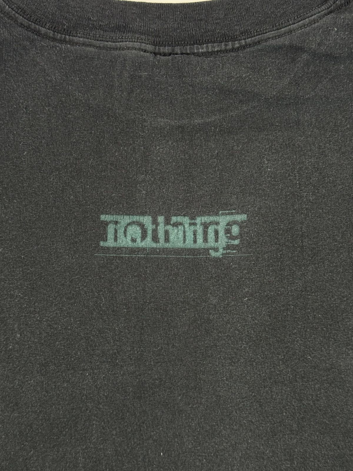 Detailaufnahme des minimalistischen, grünen „nothing“-Schriftzugs auf dem schwarzen Baumwollstoff der Rückseite.