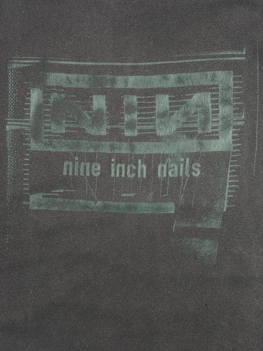 Nahaufnahme des vorderen Siebdrucks mit dem typisch verzerrten Textur-Design des legendären Nine Inch Nails Bandlogos.