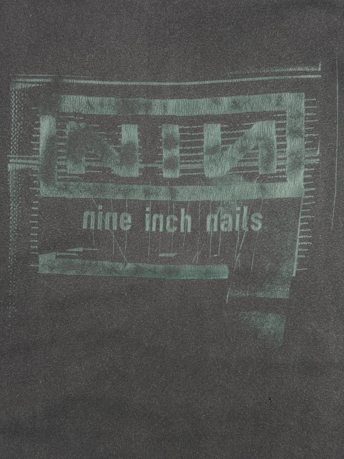 Nahaufnahme des vorderen Siebdrucks mit dem typisch verzerrten Textur-Design des legendären Nine Inch Nails Bandlogos.