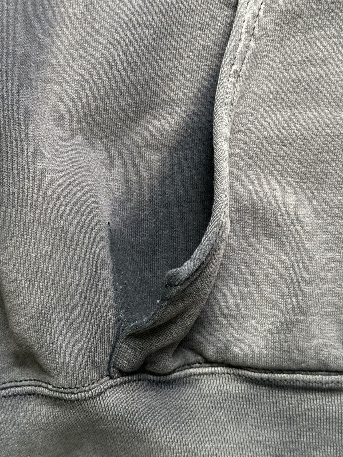 Nahaufnahme der Eingriffskante der Kängurutasche mit einem kleinen Einriss/Loch an der Nahtstelle im Thrashed-Look.