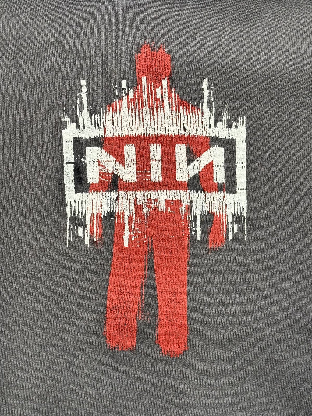 Detailansicht des vorderen Grafikprints mit der roten Personen-Silhouette und dem charakteristischen, weiß-schwarzen NIN-Kasten-Logo im Used-Look.