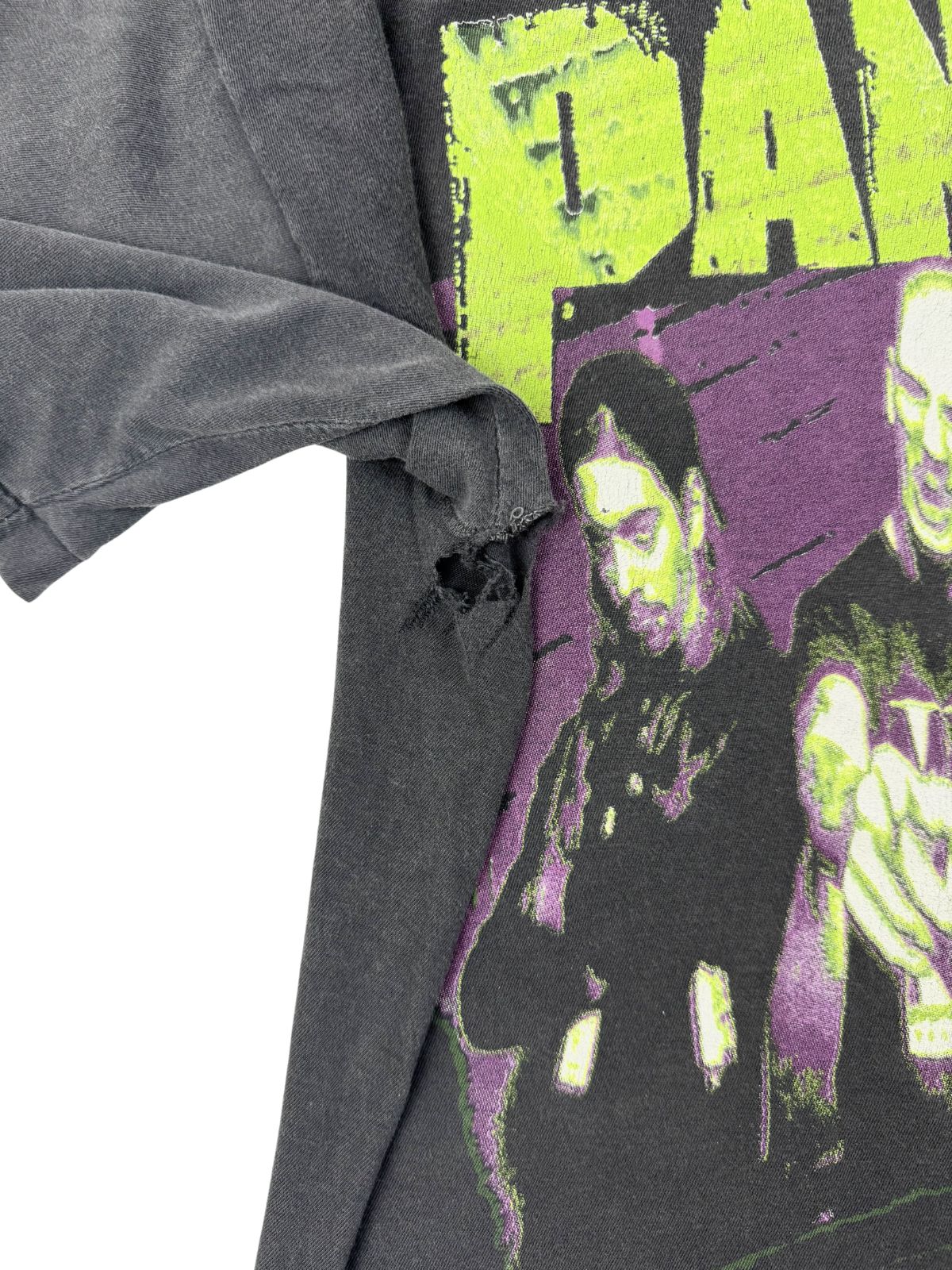 Detailaufnahme der rechten Achselregion neben dem bunten Print, die eine größere Rissbildung und starken Abnutzungscharakter (Distressed-Look) zeigt.